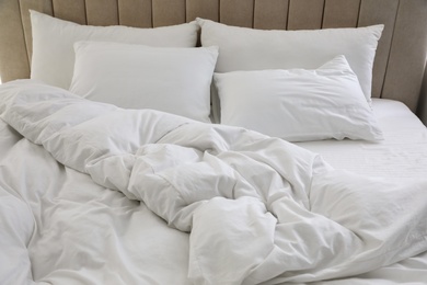 Photo of Many soft pillows and blanket on large comfortable bed