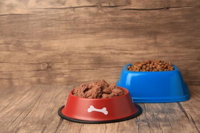 Photo of Dry and wet pet food in feeding bowls on wooden floor, space for text