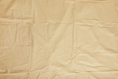 Photo of Crumpled beige fabric as background, top view