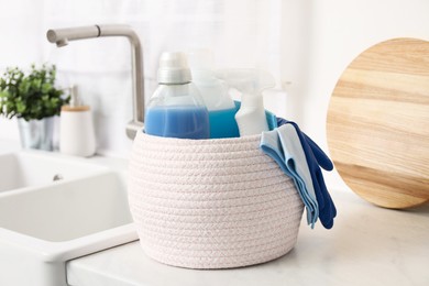 Different cleaning supplies in basket on countertop