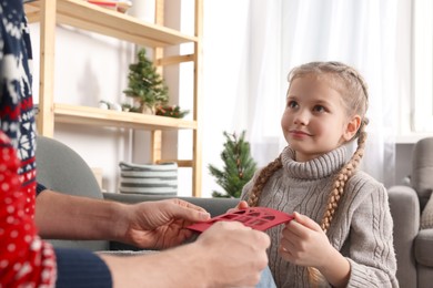 Photo of Man receiving greeting card from his daughter at home
