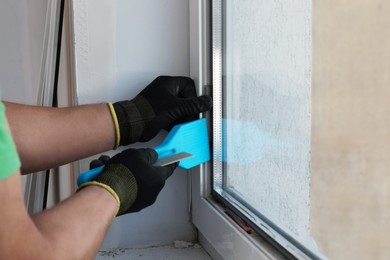 Photo of Worker in uniform installing pvc window, closeup