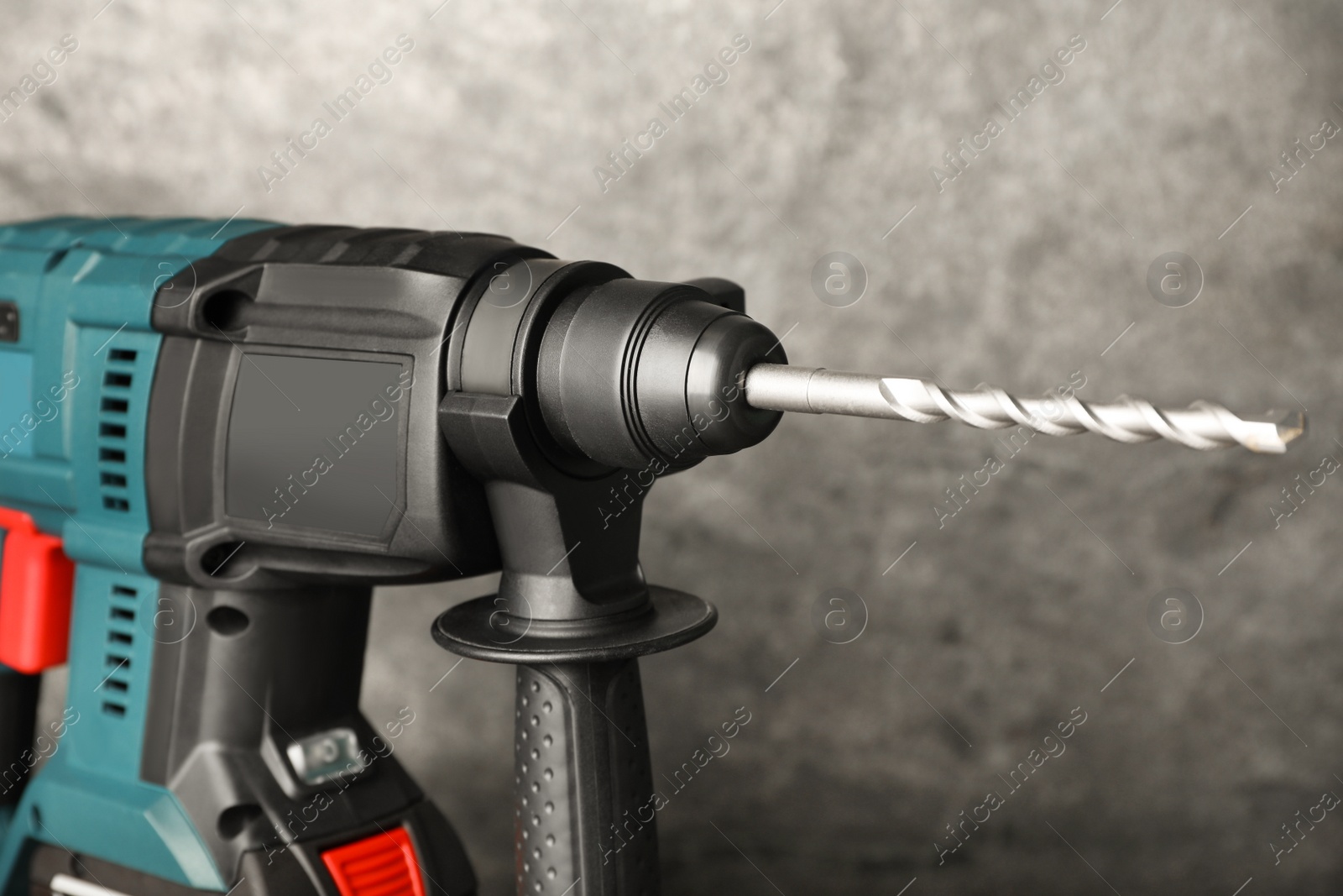 Photo of Modern electric power drill near grey wall, closeup