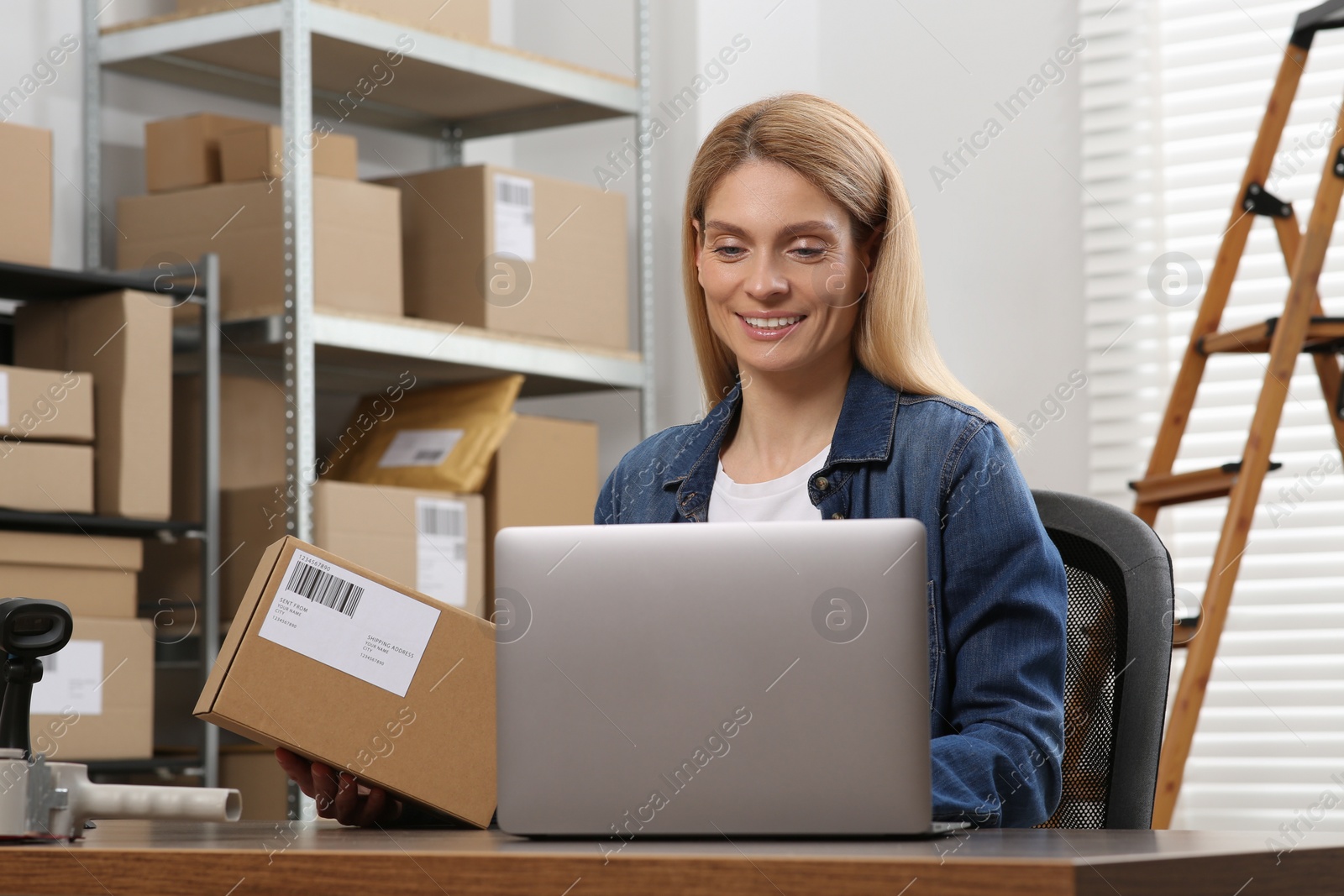 Photo of Seller with parcel and laptop in office. Online store