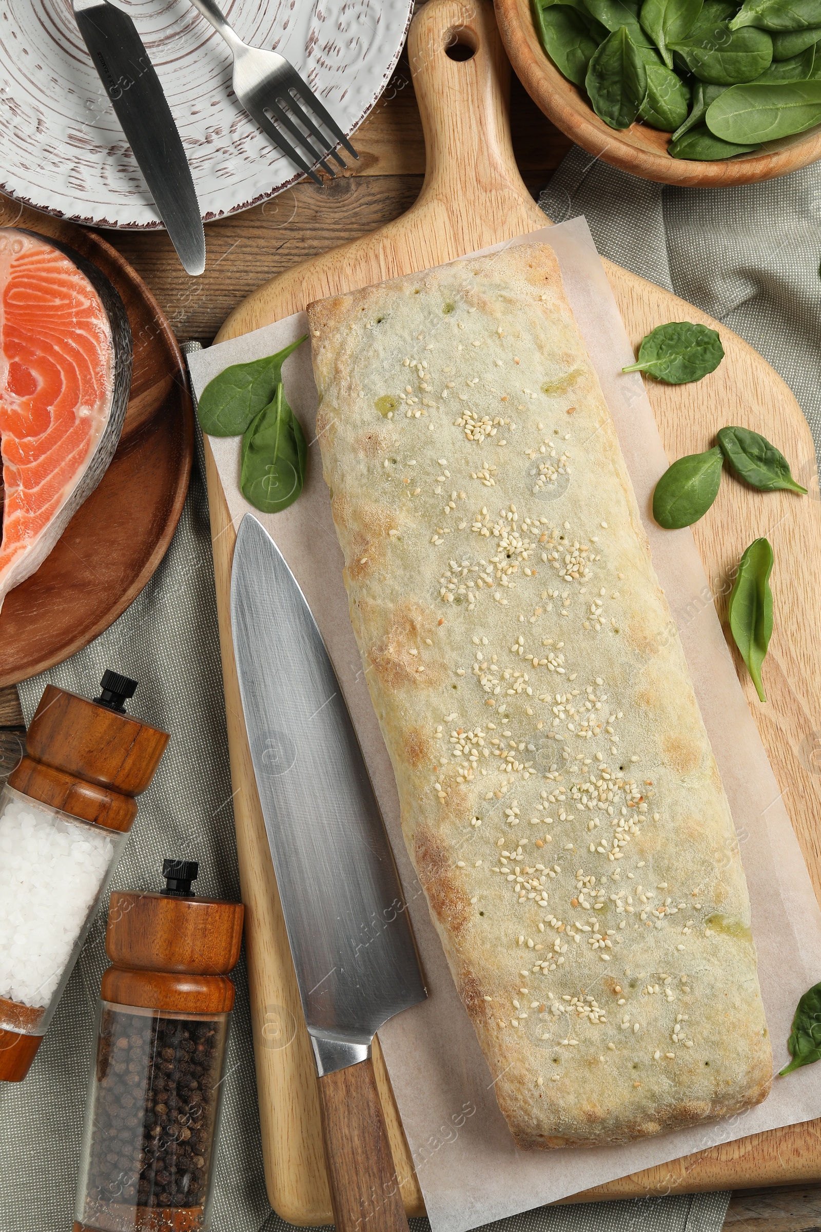 Photo of Delicious strudel with salmon and spinach on wooden table, flat lay