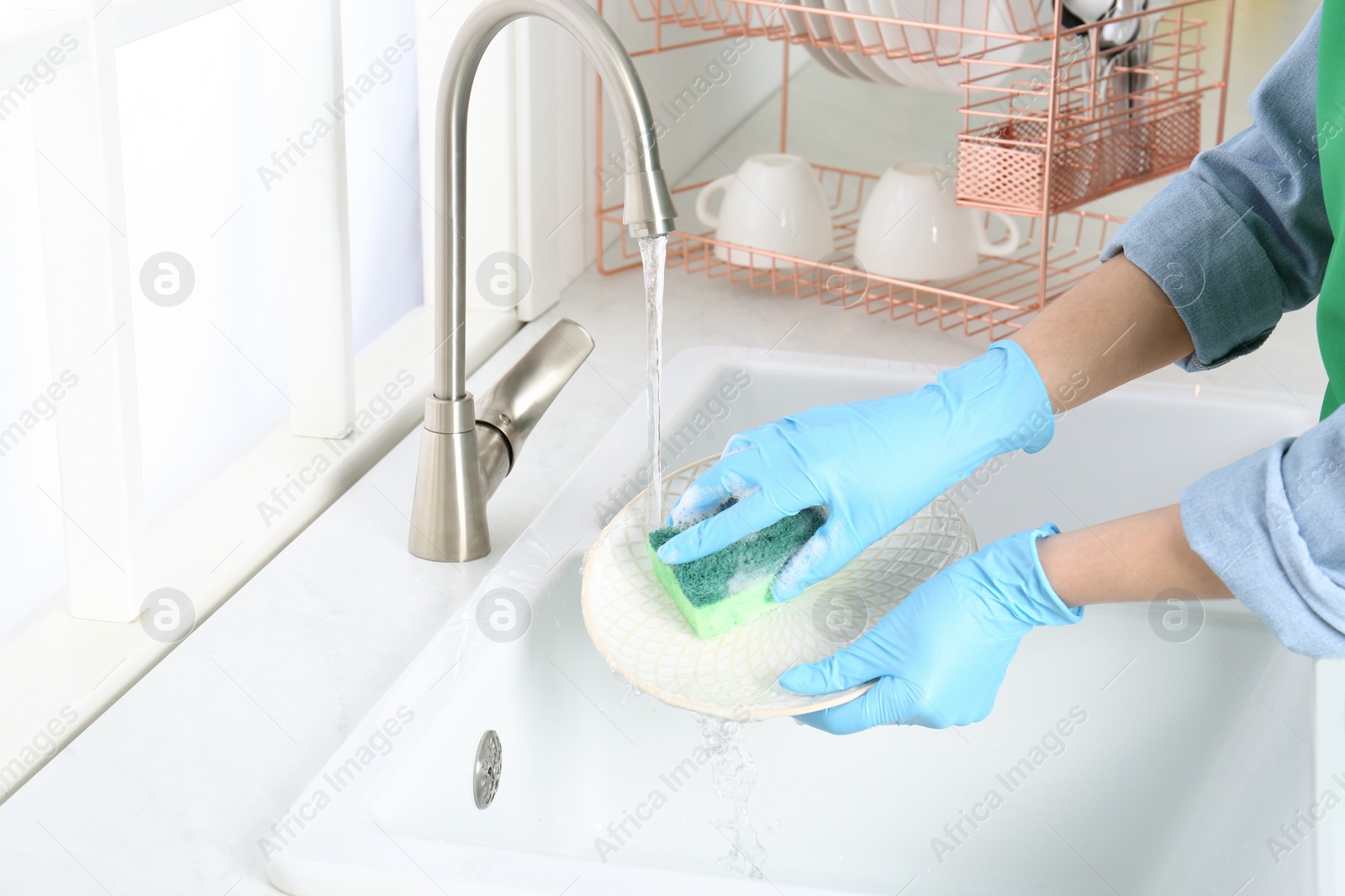 Photo of Woman washing plate in modern kitchen, closeup