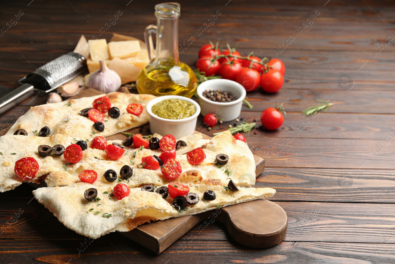 Photo of Focaccia bread with olives and tomatoes on wooden table