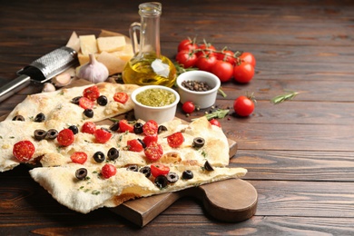 Photo of Focaccia bread with olives and tomatoes on wooden table