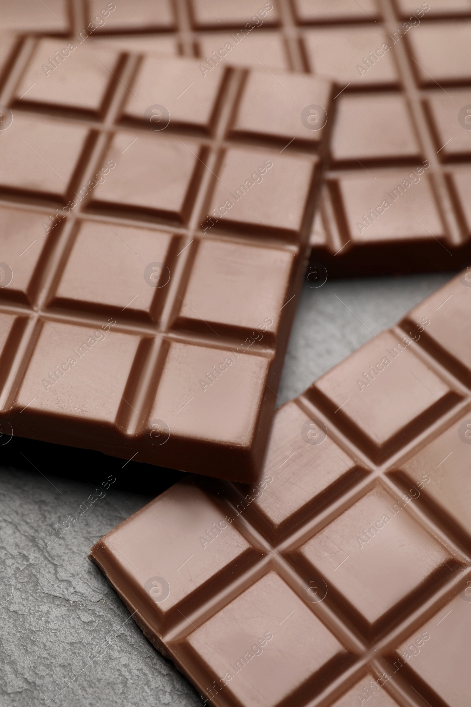 Photo of Delicious milk chocolate bars on black table, closeup