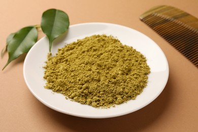Photo of Henna powder, comb and green leaves on coral background. Natural hair coloring