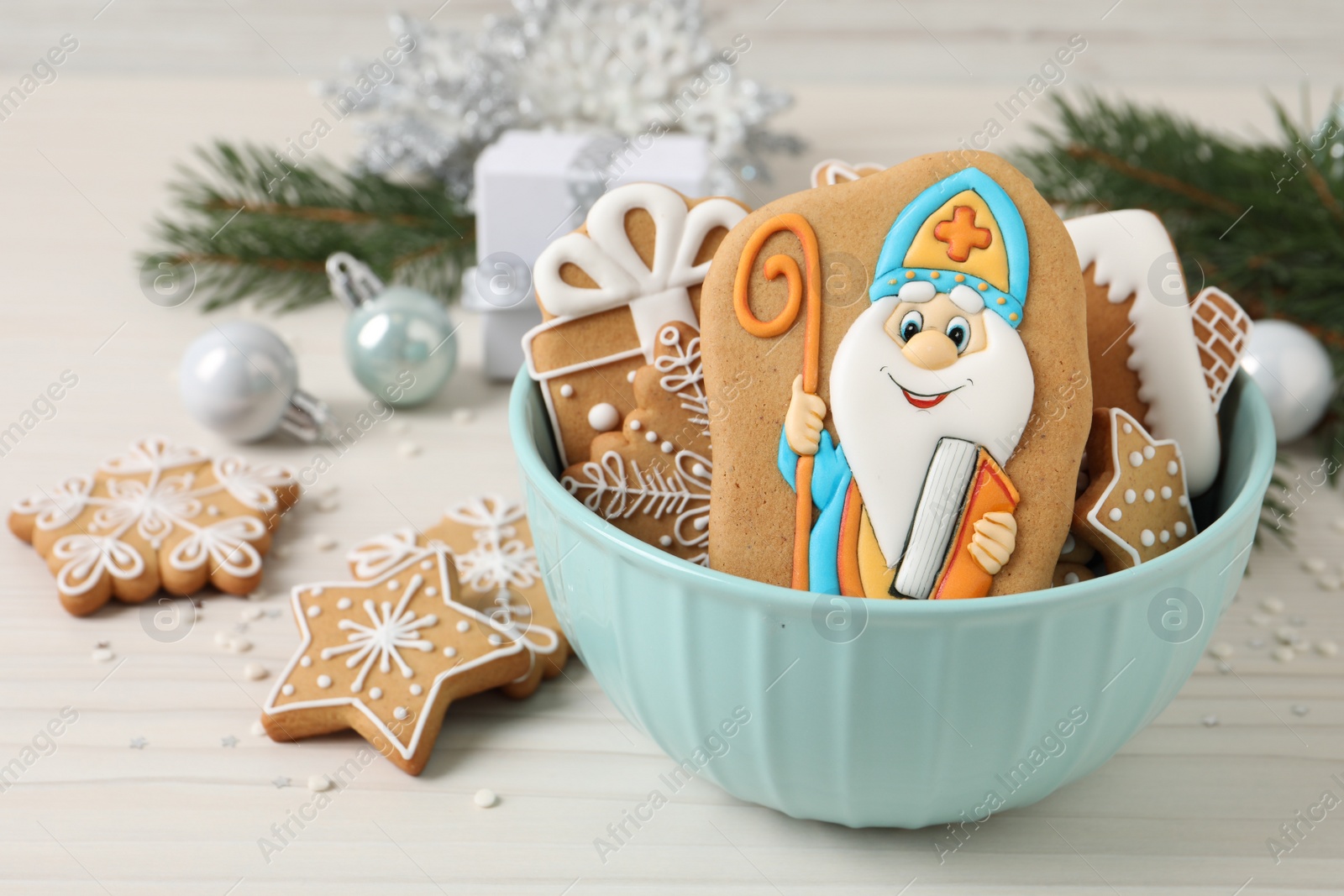 Photo of Tasty gingerbread cookies and festive decor on white wooden table. St. Nicholas Day celebration