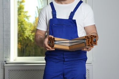 Installation worker with sample of modern window profile indoors