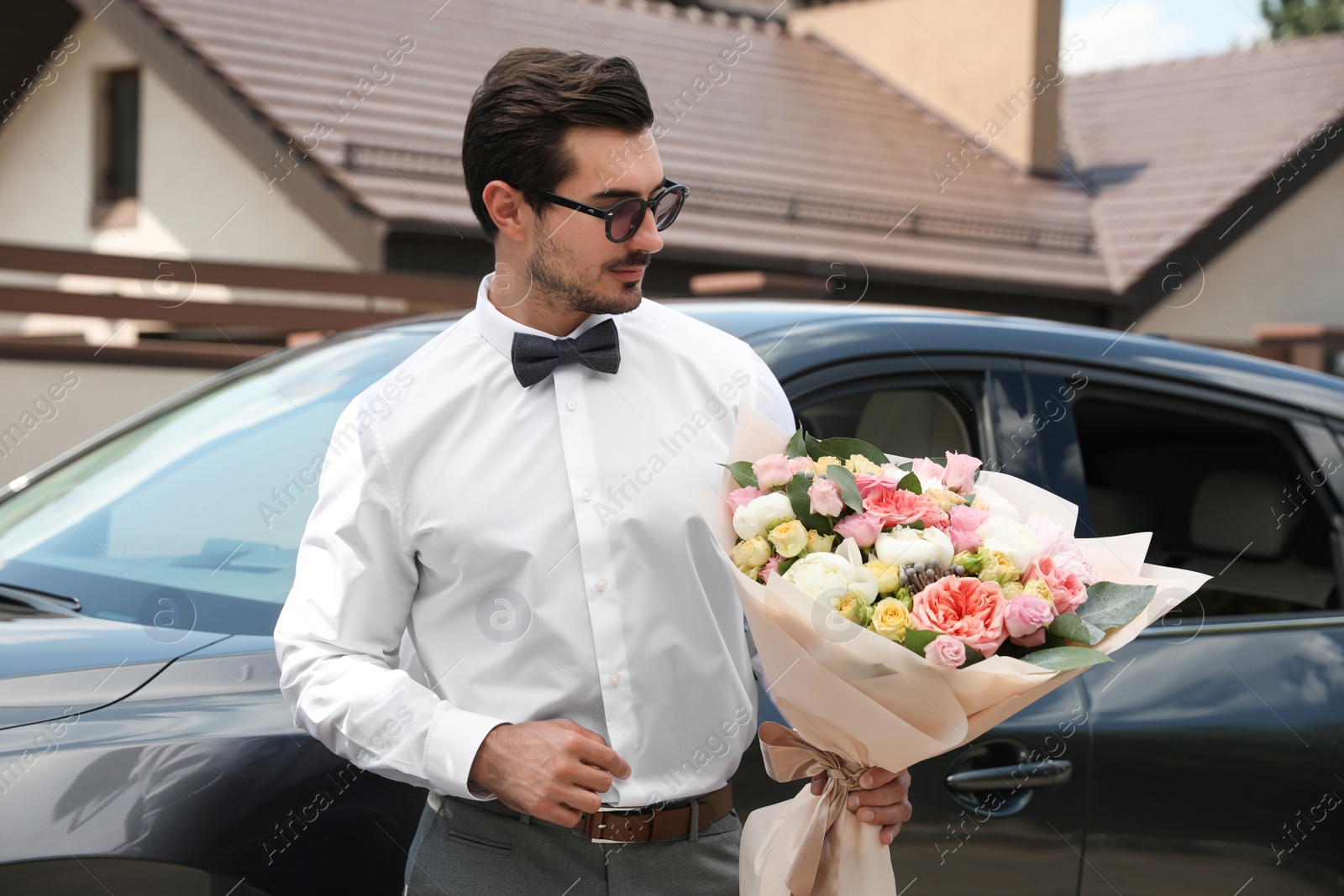 Photo of Young handsome man with beautiful flower bouquet near car outdoors