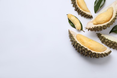 Photo of Pieces of fresh ripe durian and leaves on white background, flat lay. Space for text