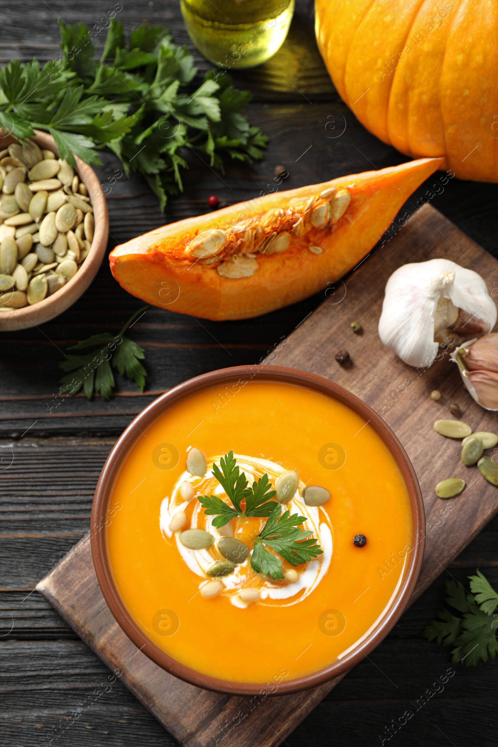 Photo of Delicious pumpkin soup in bowl on wooden table, flat lay