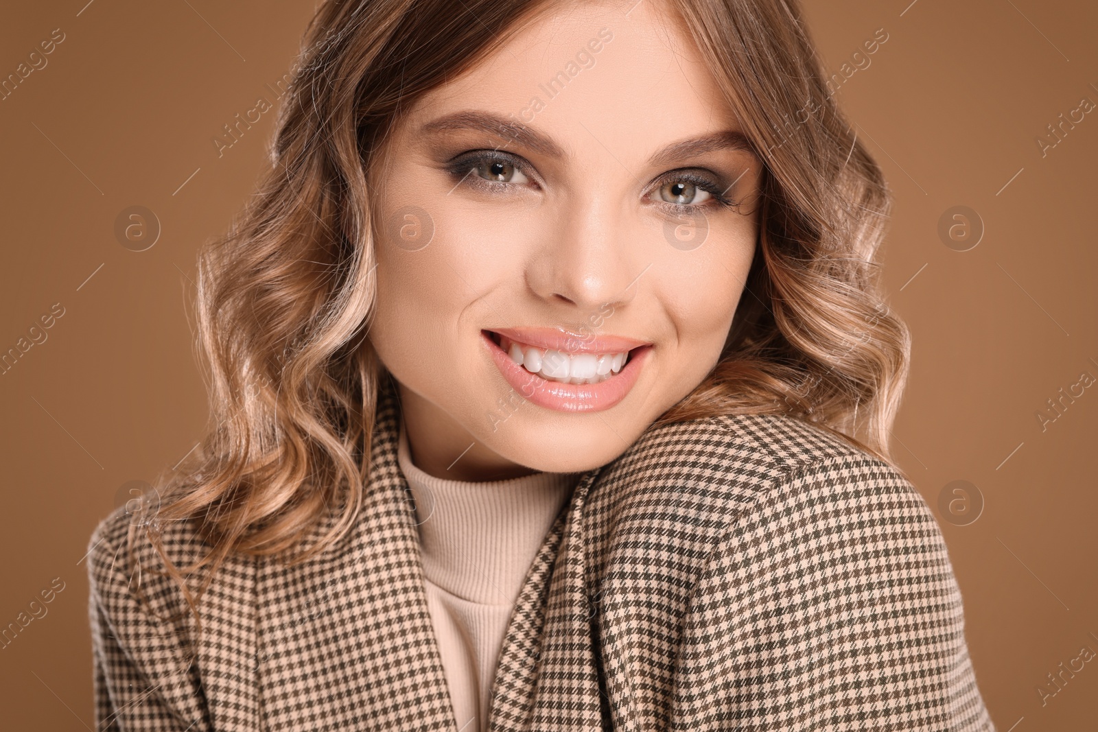 Photo of Portrait of young woman with beautiful makeup on light brown background, closeup