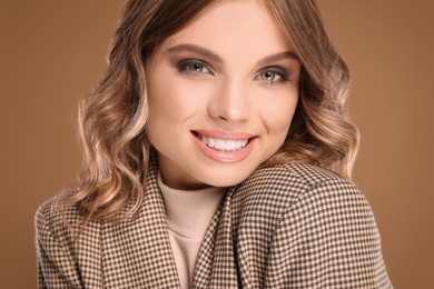 Portrait of young woman with beautiful makeup on light brown background, closeup