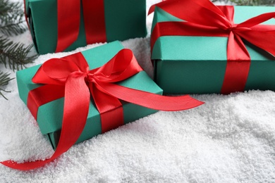 Photo of Gift boxes and Christmas tree branches on table with artificial snow