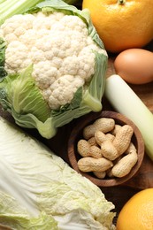 Photo of Healthy meal. Different vegetables and peanuts on wooden table, closeup