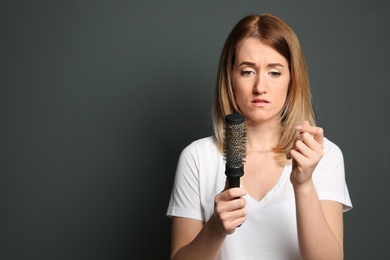 Young woman with hair loss problem on gray background