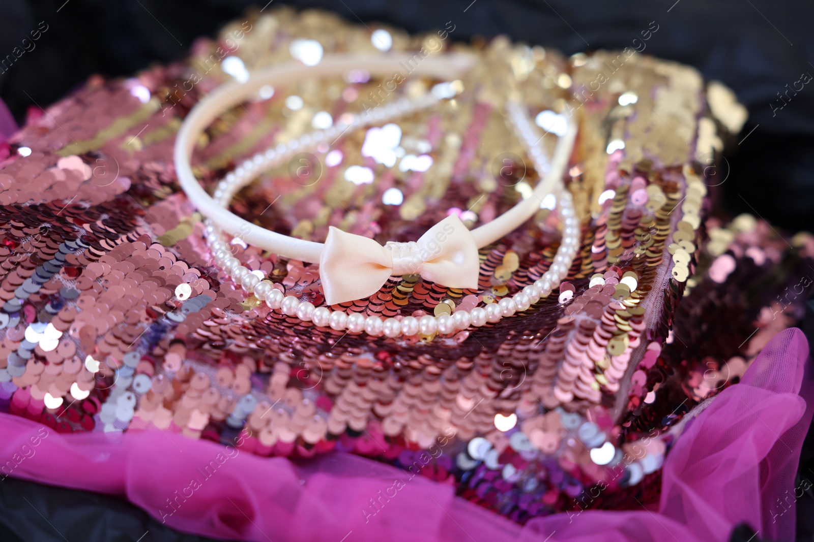 Photo of Headbands and stylish pink carnival costume with sequins in black box, closeup