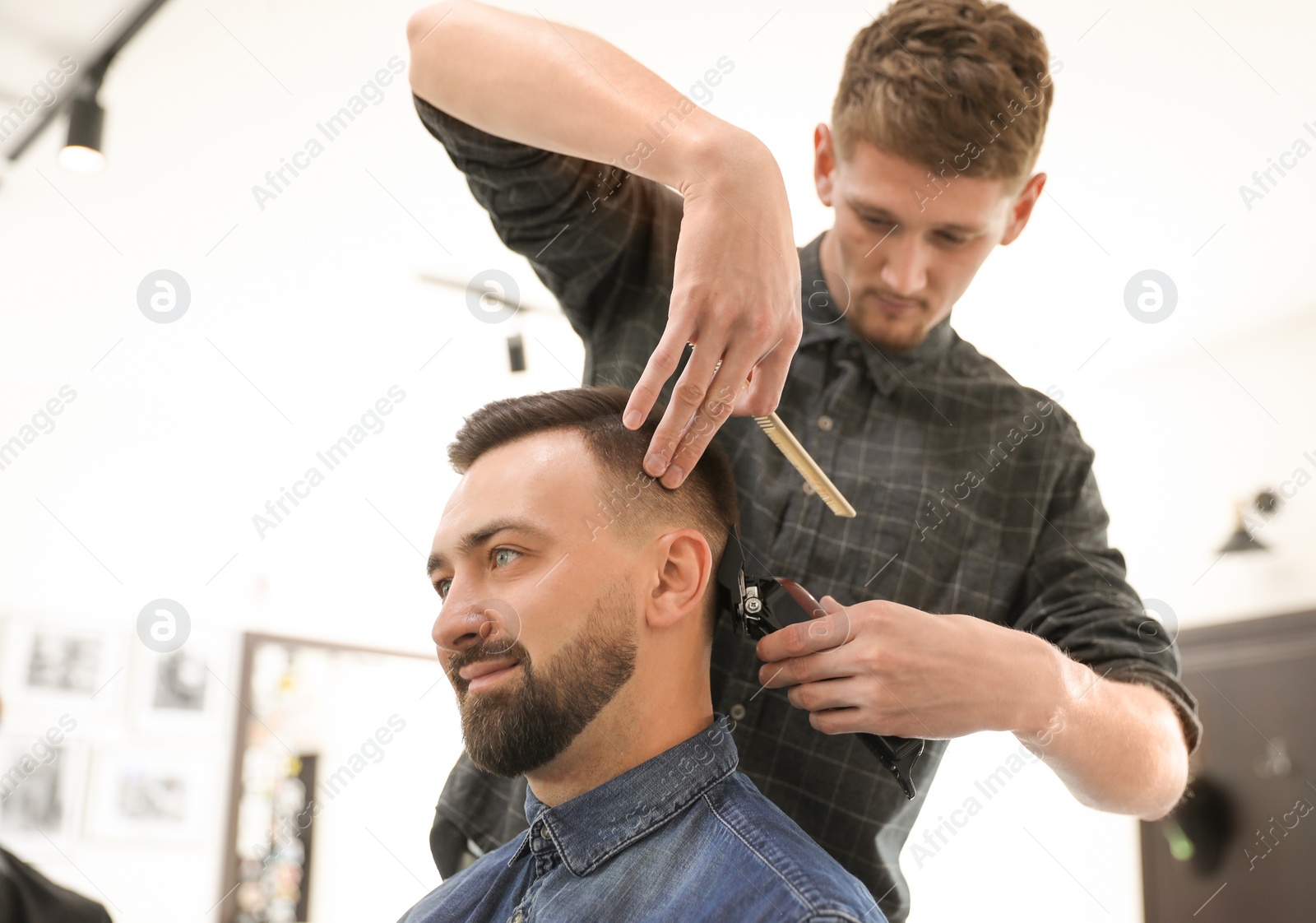 Photo of Professional barber working with client in hairdressing salon. Hipster fashion