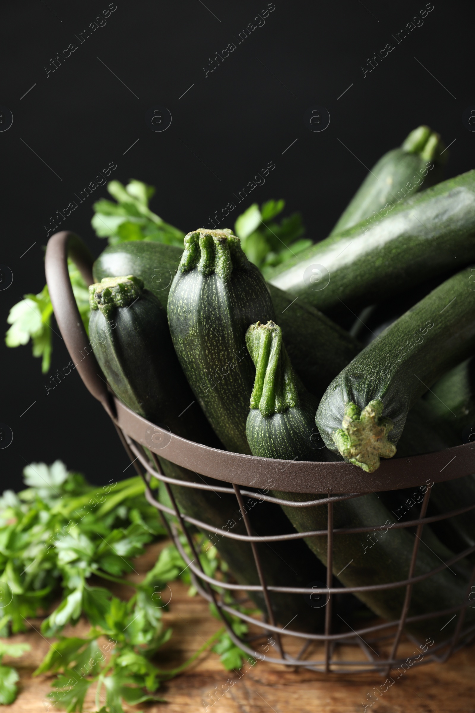 Photo of Basket with green zucchinis on wooden table, closeup