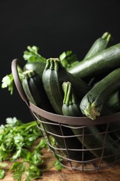 Photo of Basket with green zucchinis on wooden table, closeup