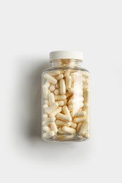 Photo of Transparent bottle with pills on white background, top view