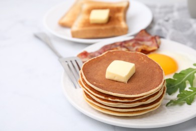 Photo of Tasty pancakes served with fried egg and bacon on white table, space for text