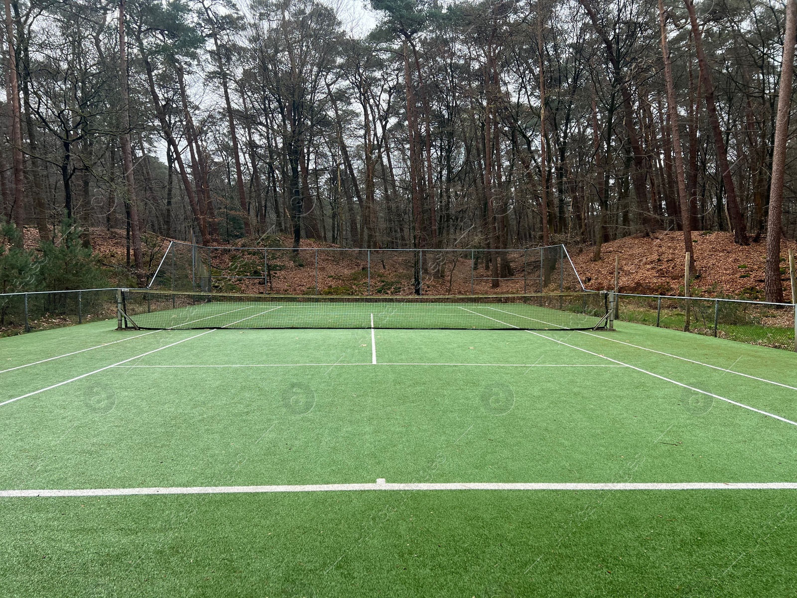 Photo of Tennis court with artificial grass and net outdoors