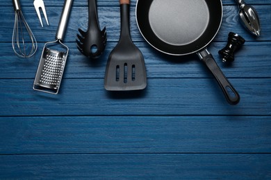 Set of different kitchen utensils on blue wooden table, flat lay. Space for text