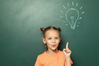 Photo of Little school child near chalkboard with lightbulb drawing