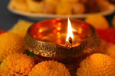 Photo of Diwali celebration. Diya lamp and chrysanthemum flowers on table, closeup
