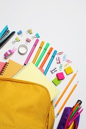 Backpack with different school stationery on white background, flat lay