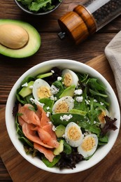 Photo of Delicious salad with boiled eggs, salmon and cheese served on wooden table, flat lay