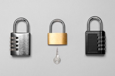 Photo of Different padlocks and key on grey background, flat lay