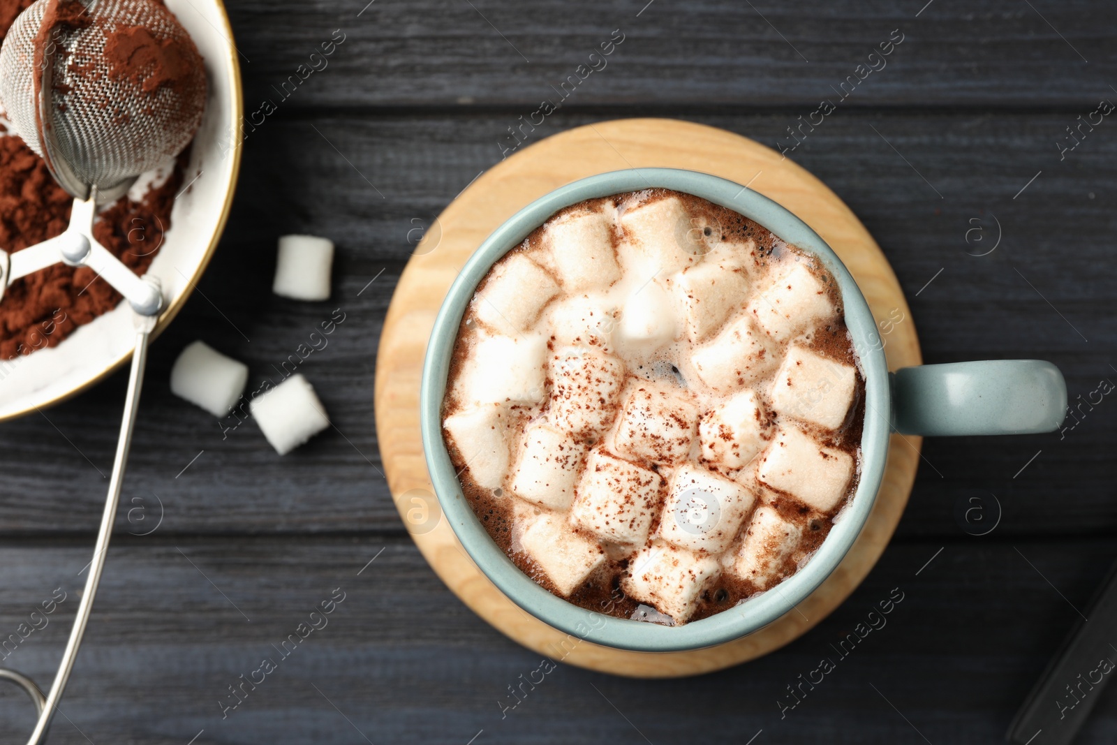 Photo of Cup of aromatic hot chocolate with marshmallows and cocoa powder on dark gray wooden table, flat lay