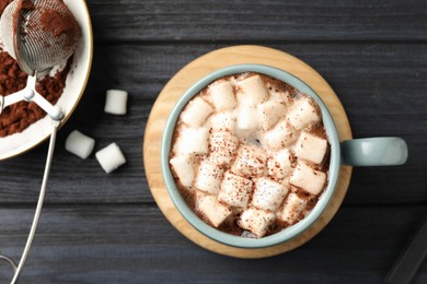 Cup of aromatic hot chocolate with marshmallows and cocoa powder on dark gray wooden table, flat lay