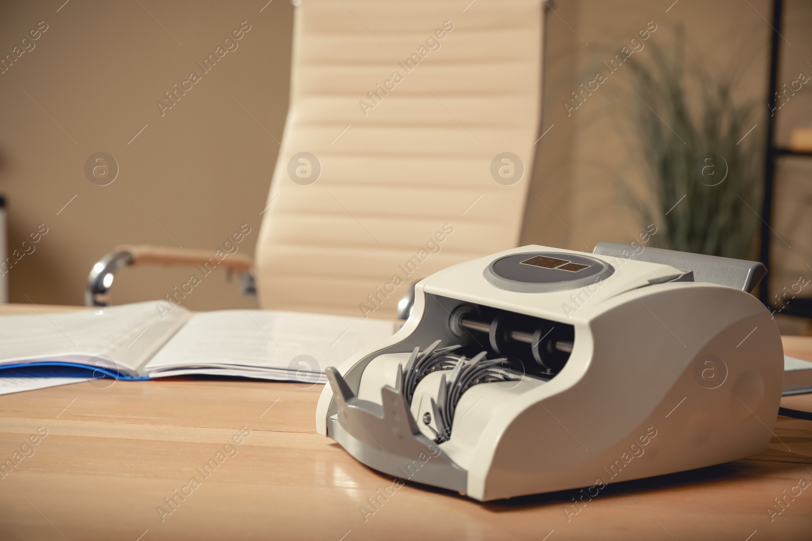 Photo of Modern banknote counter on wooden table indoors. Space for text