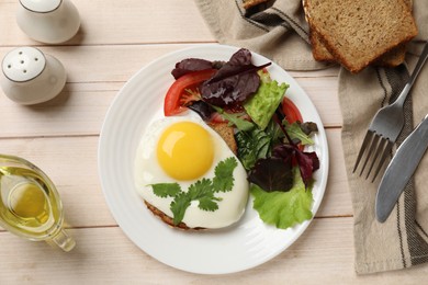 Delicious breakfast with fried egg and salad served on light wooden table, flat lay