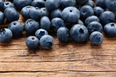 Photo of Many tasty fresh blueberries on wooden table, closeup