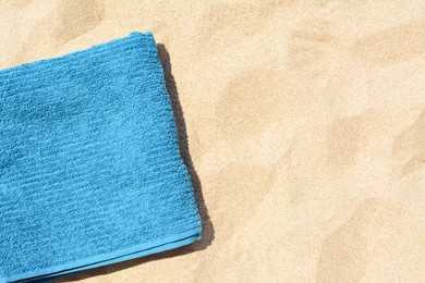 Soft blue beach towel on sand, top view. Space for text