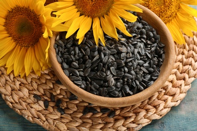 Photo of Bowl with sunflower seeds on wicker mat