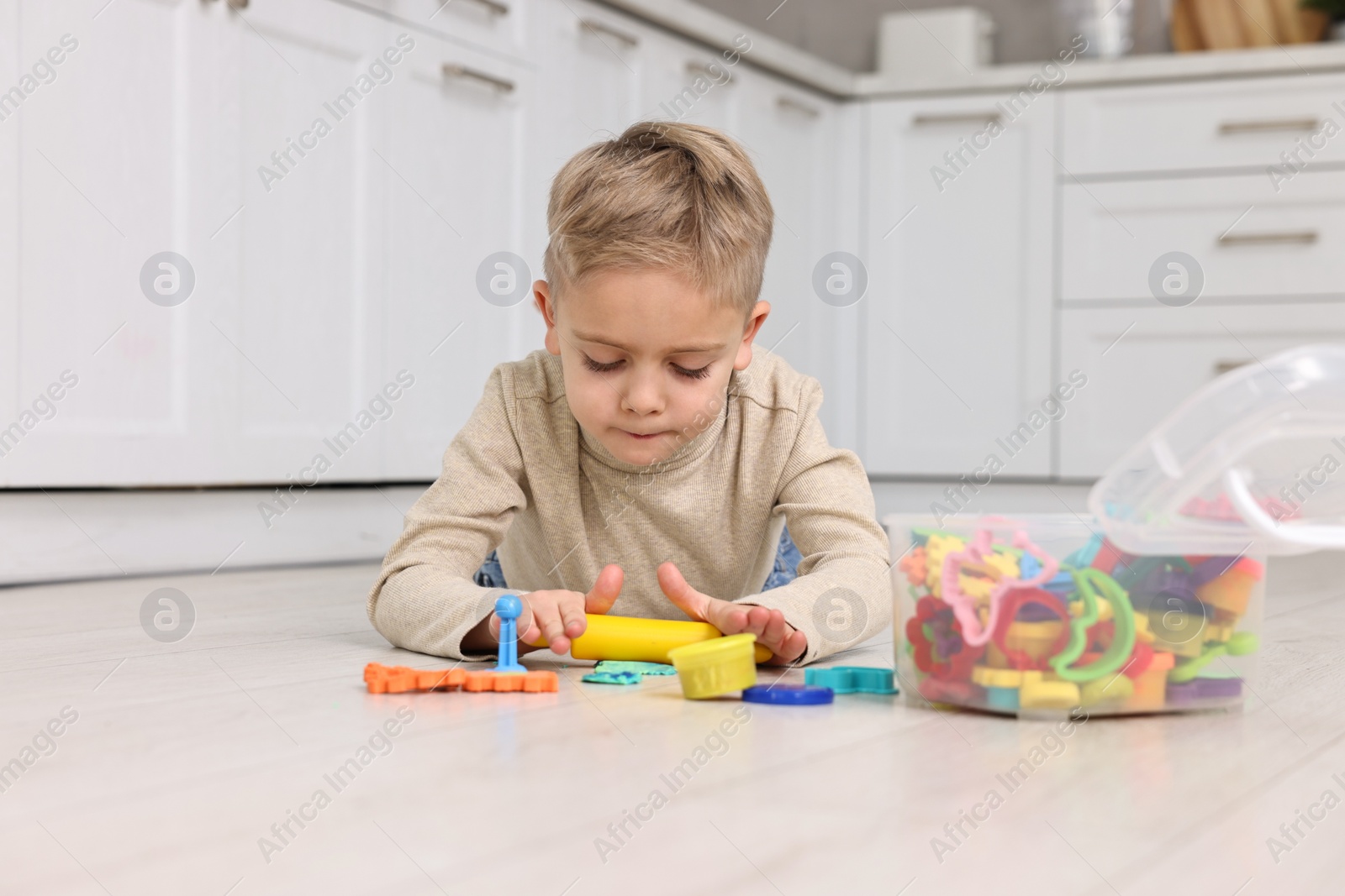 Photo of Cute little boy playing on warm floor in kitchen. Heating system