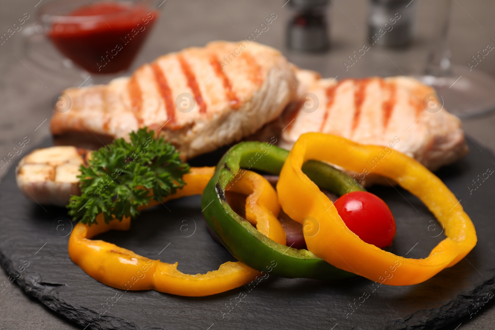 Photo of Grilled meat with garnish on slate plate, closeup