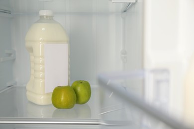 Gallon of milk and apples n refrigerator, closeup