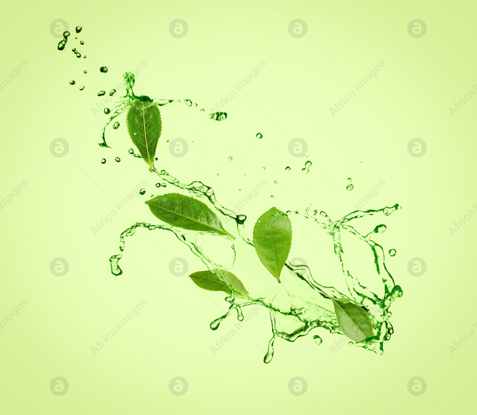 Image of Splashes of refreshing drink with leaves on pale green background. Green or matcha tea