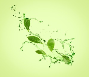 Splashes of refreshing drink with leaves on pale green background. Green or matcha tea