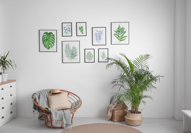 Photo of Beautiful paintingstropical leaves on white wall in living room interior